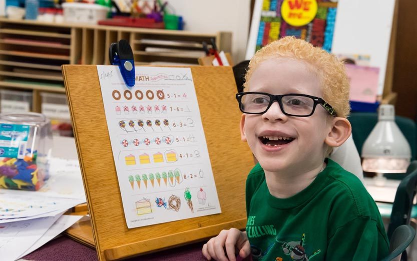 Young boy sitting at school desk smiling