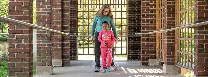 Young girl learning to use cane while walking