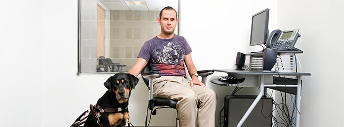 Man sitting in an office next to guide dog