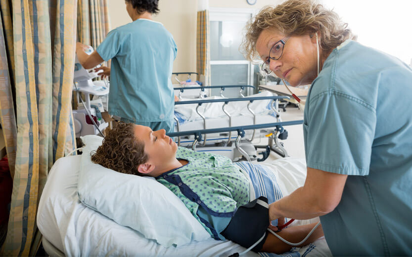 a nurse tending to a boy in a hospital bed after surgery