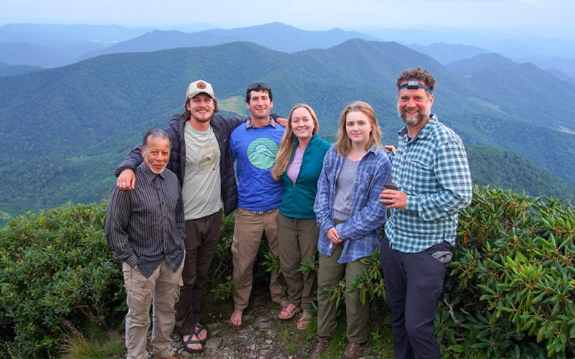 a group of volunteers smiling for a photo with a beautiful valley behind them