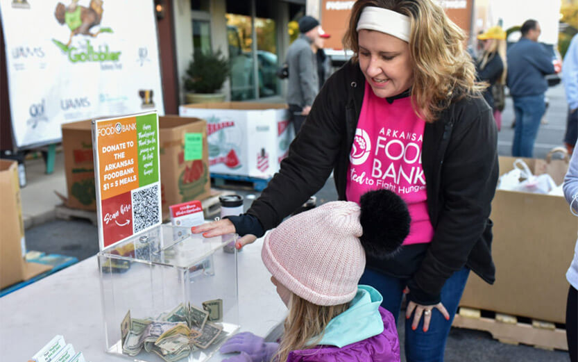 volunteer talking to a girl about the donation box at an event