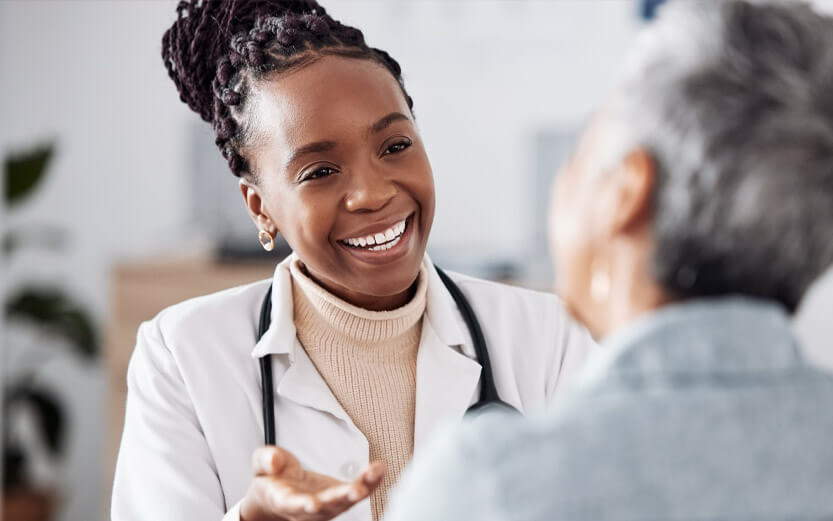 close up of a black doctor smiling while talking to her patient