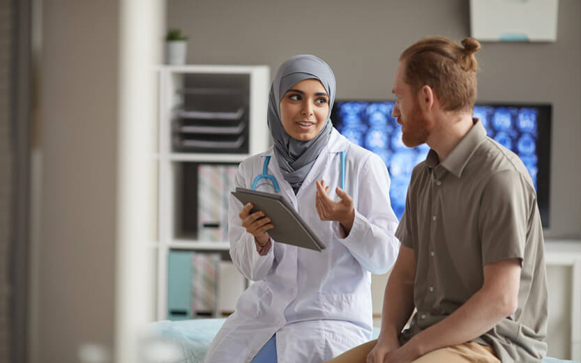 a doctor wearing a headscarf talking to a patient in an exam room