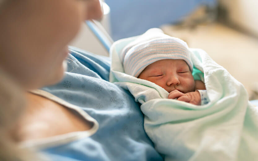 close up of a newborn in their mother's arms