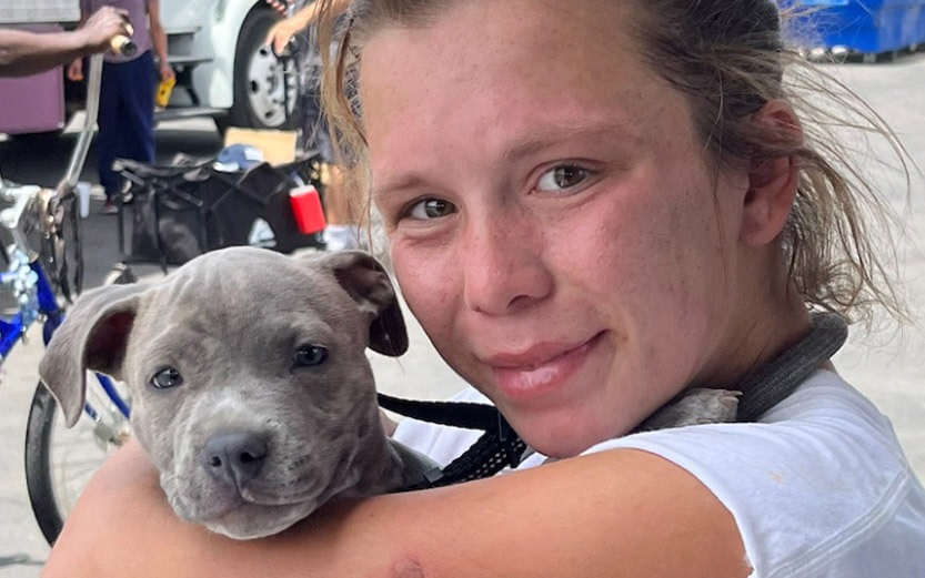 a girl with tears of joy holding a cute gray pit puppy