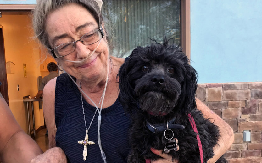 a senior woman holding her black dog