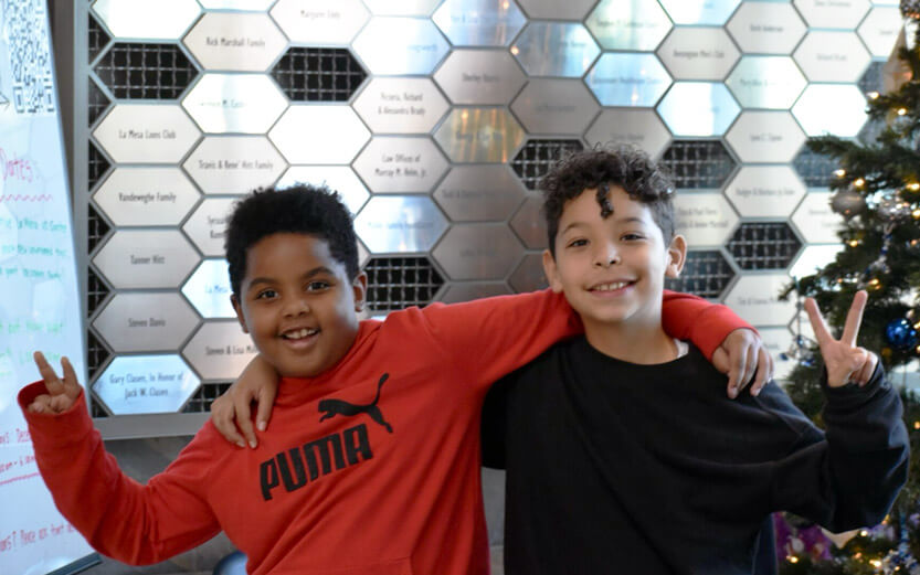 two boys with arms around each other making pease signs