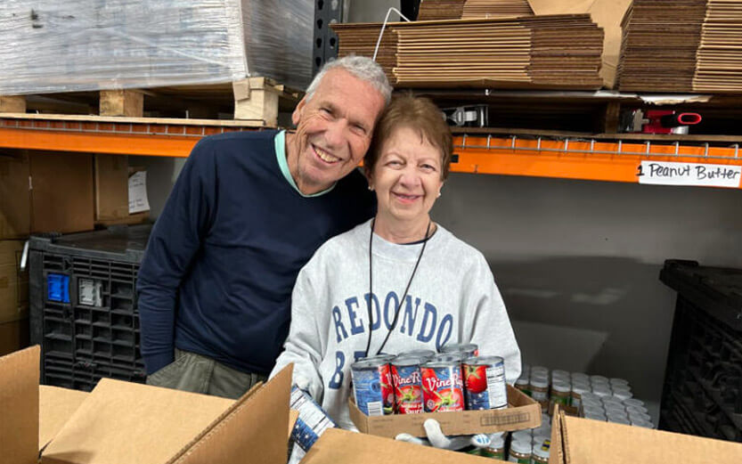 two volunteers packing boxes of food for distribution