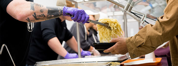 close up of a volunteer serving pasta
