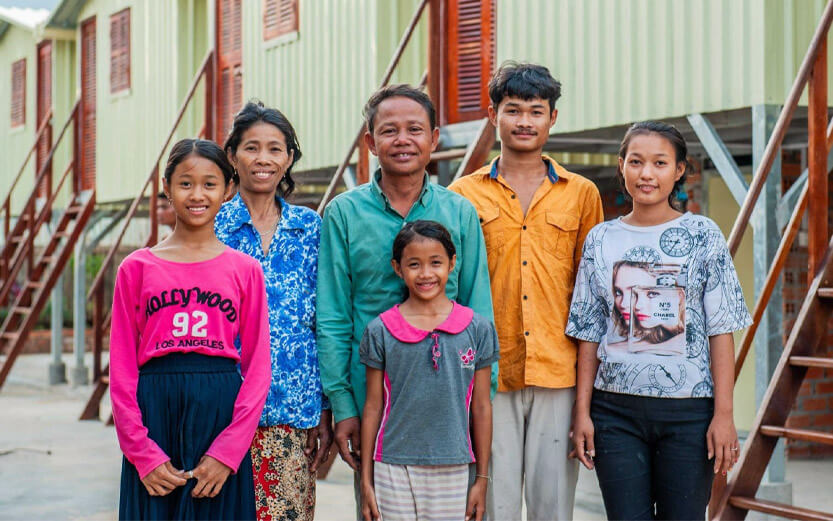 a family of six standing in front of new housing