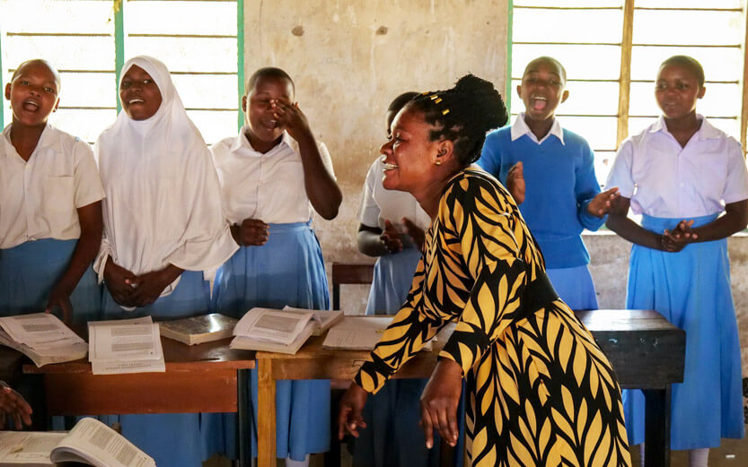 a teacher dancing in front of a group of singing students