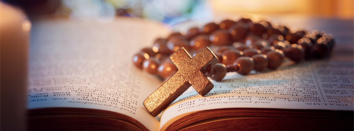 close up of a wood rosary sitting on an open bible