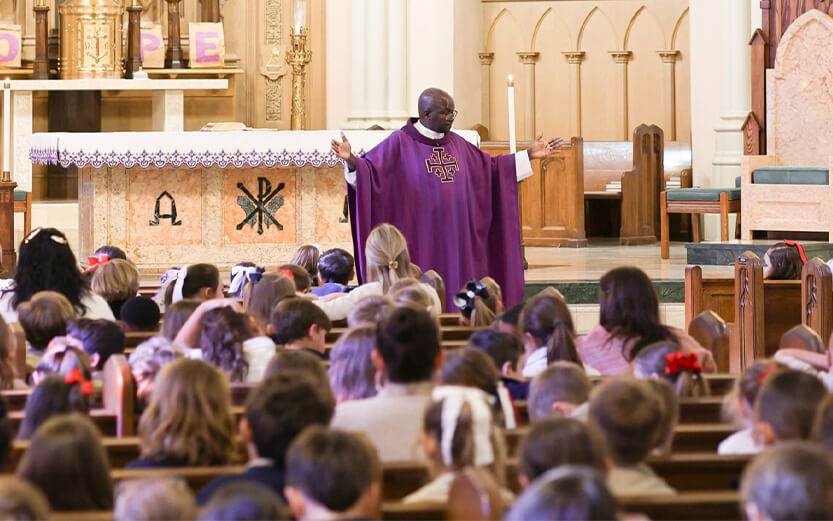 religious leader in a purple chasuble celebrating mass for a congregation of children