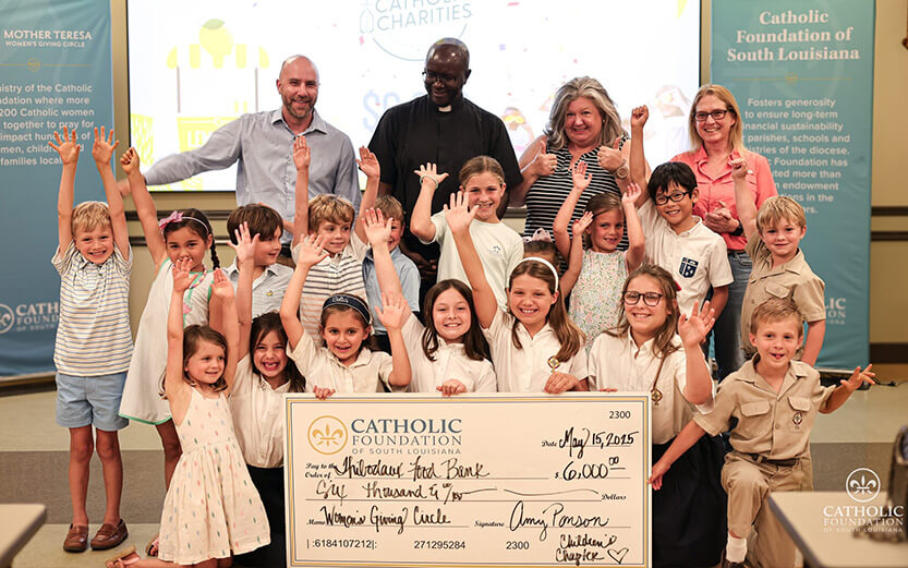 a group of children and adults participating in a check presentation for the Catholic Foundation of South Louisiana