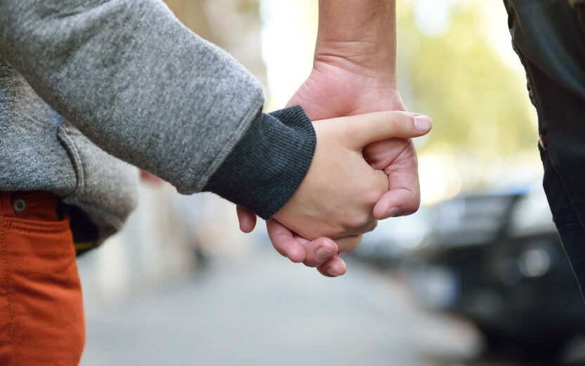 closeup of kid and dad holding hands