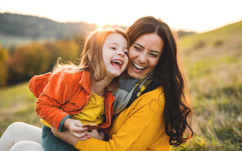 woman laughing with young girl outdoors
