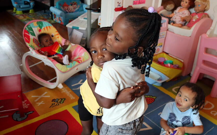 two young children hugging each other in a play room