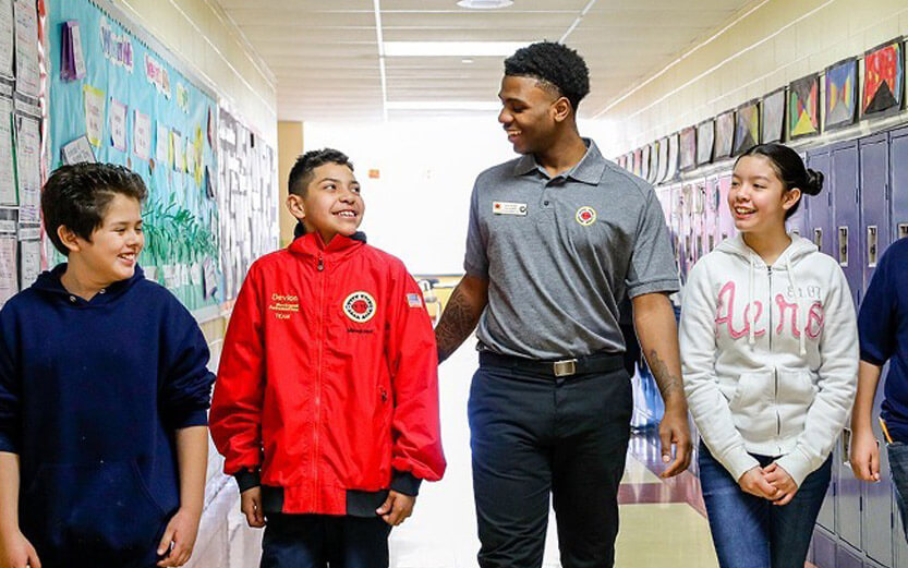 City Year volunteer walking down a school hallway with students