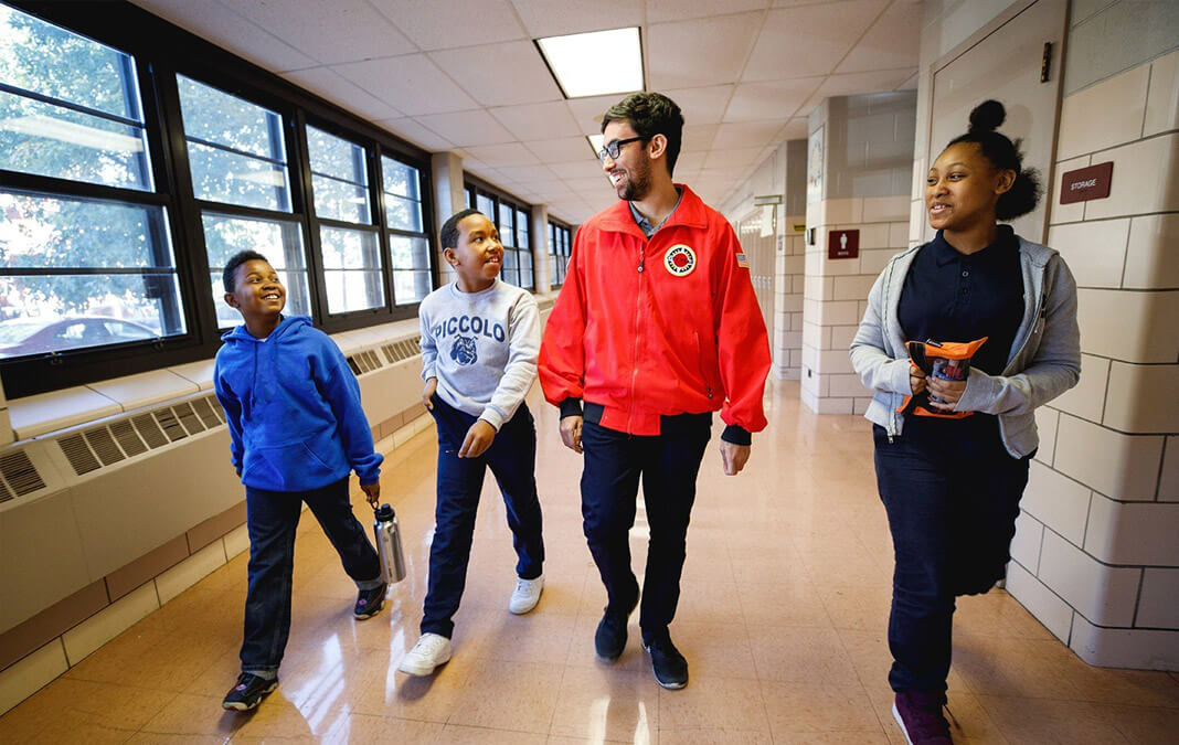 City Year volunteer walking with students down a school hallway