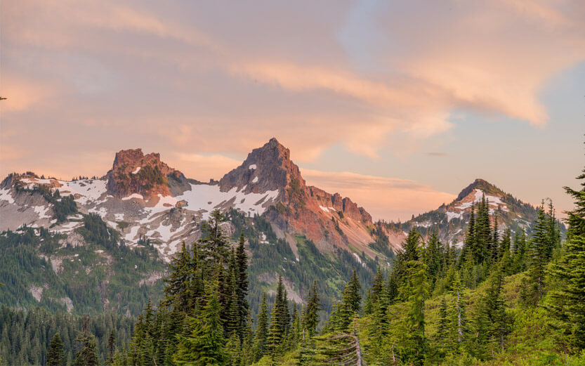 mountain peaks at sunset with forest in foreground