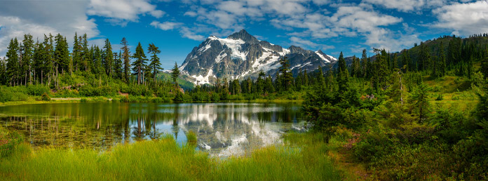 a mountain with residual snow reflecting in a lake