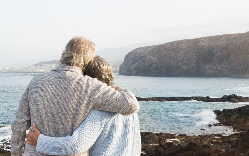 view from behind of a senior couple enjoying an ocean view