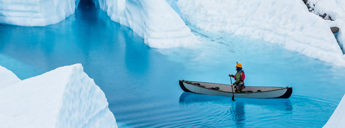 a person in a canoe steering through glacial water
