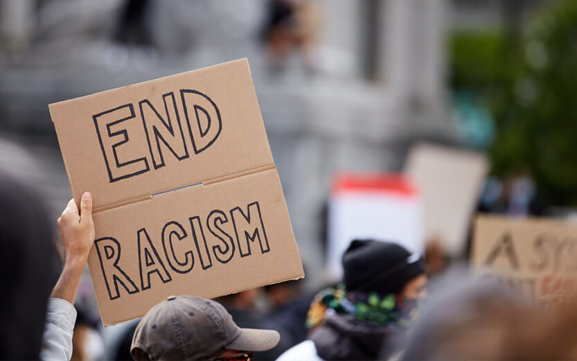 close up of a hand holding a sign that reads End Racism