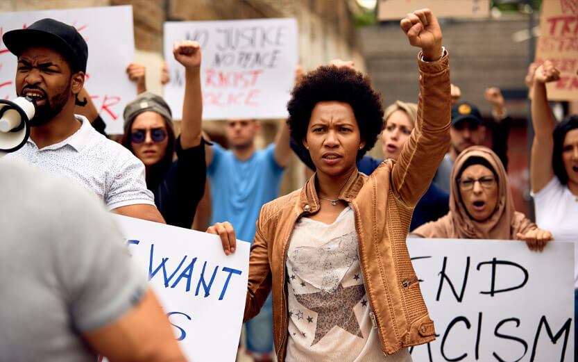 a group of racial justice demonstrators with focus on a black woman with her fist raised