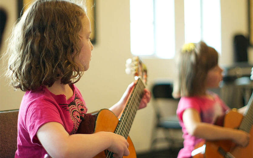 two little girls playing guitars in a room