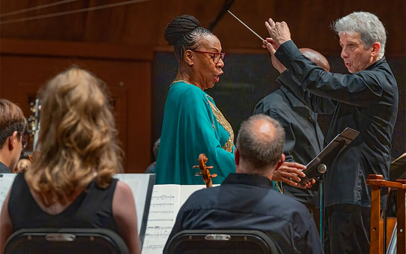 a woman singing in front of a conductor