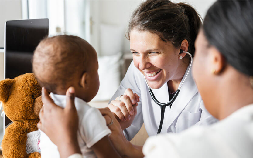 a doctor wearing a stethoscope smiling at a baby