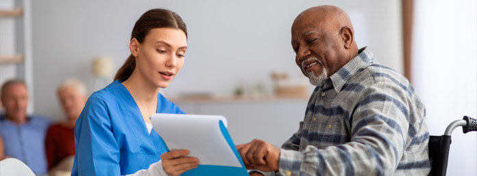 a doctor showing her clipboard to a patient in a wheelchair