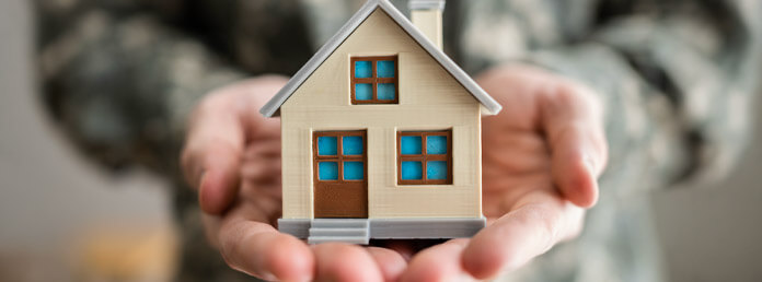 closeup of two cupped hands holding a miniature house