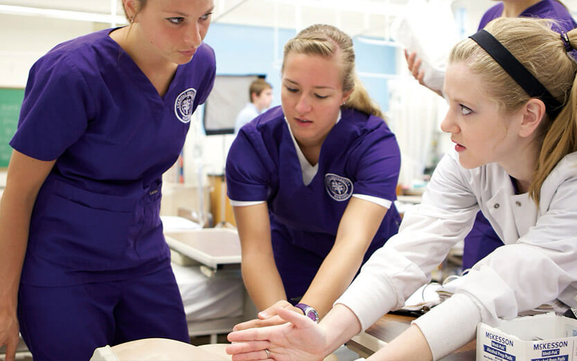 a nursing instructor giving a demonstration to two students