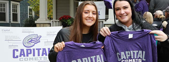 two students holding purple Capital Comets tshirts