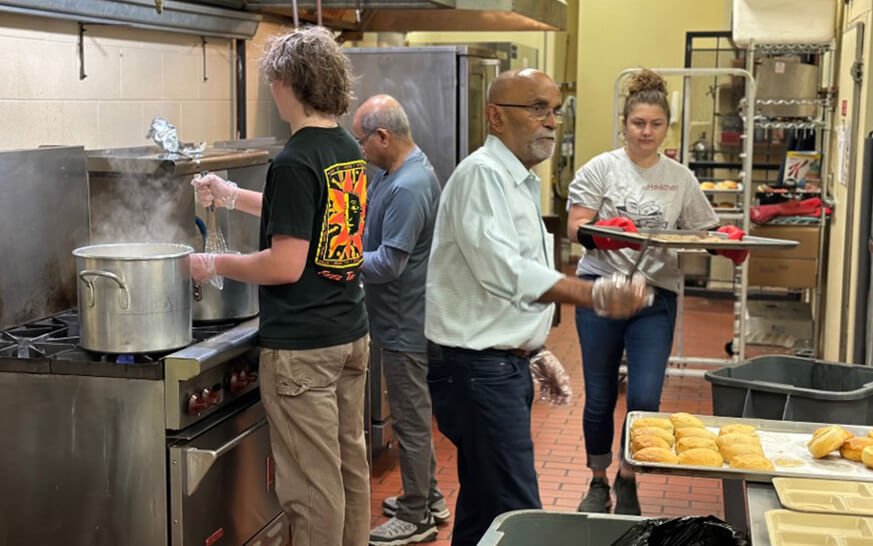 people preparing and serving meals in a industrial kitchen