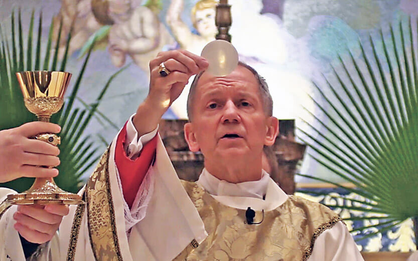 a priest holding up a wafer