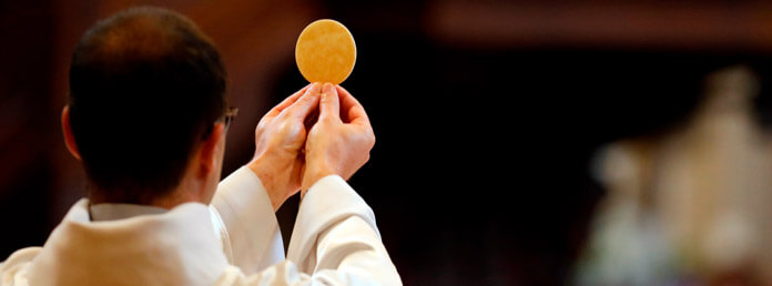 a priest holding up a wafer