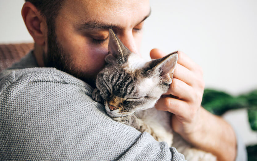 a man snuggling with a cat he's holding