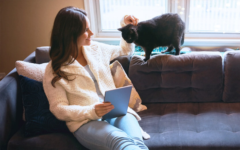 a woman sitting on a couch petting her black cat