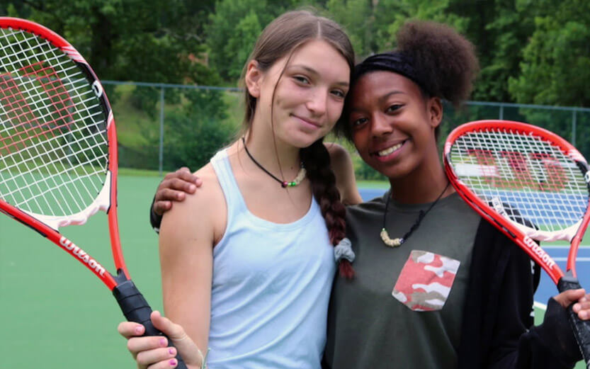 two girls with tennis rackets smiling