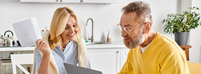 couple at the kitchen table looking at a laptop