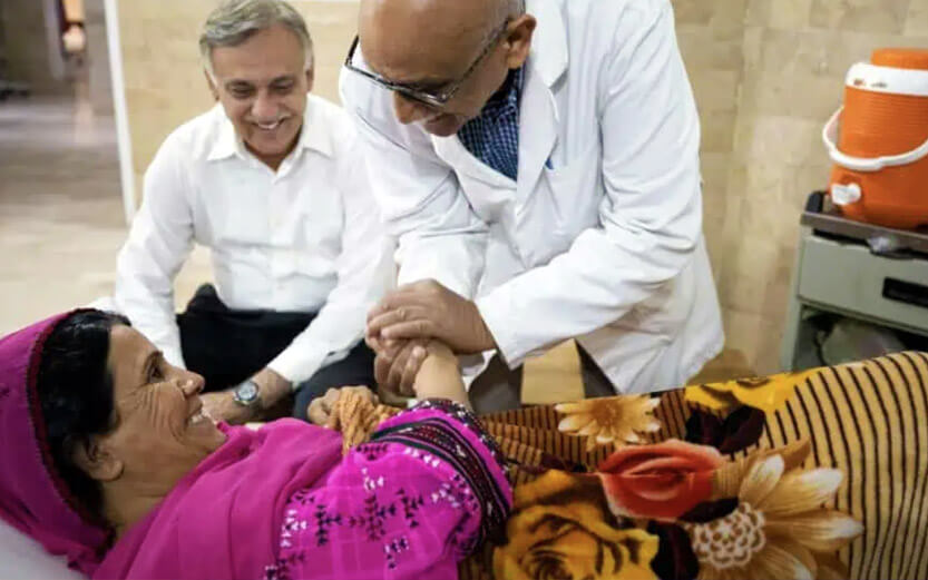 woman on hospital bed smiling at doctors