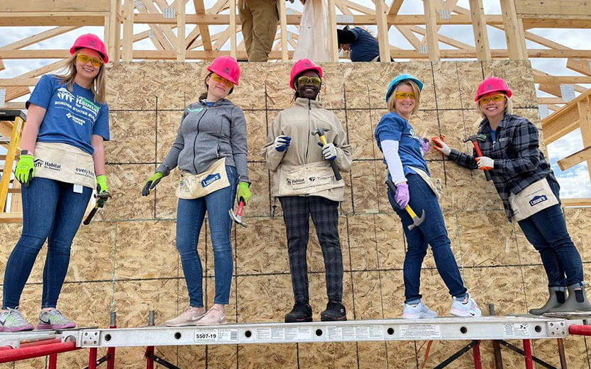 A group of adults standing on a new home construction site.