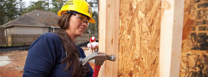 An adult using a hammer on a new home build.