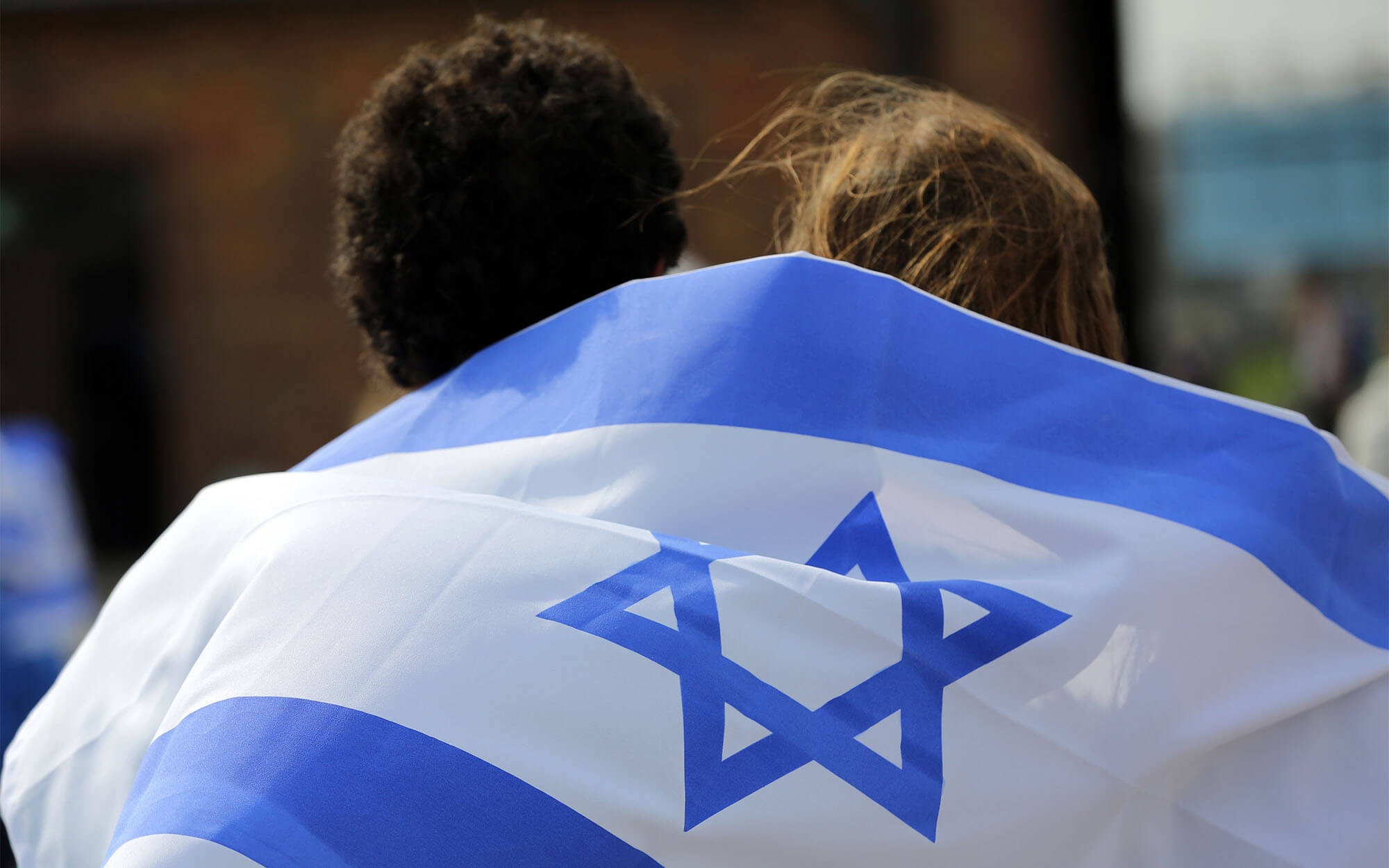 Two people wrapped in the flag of Israel at International Holocaust Remembrance Day