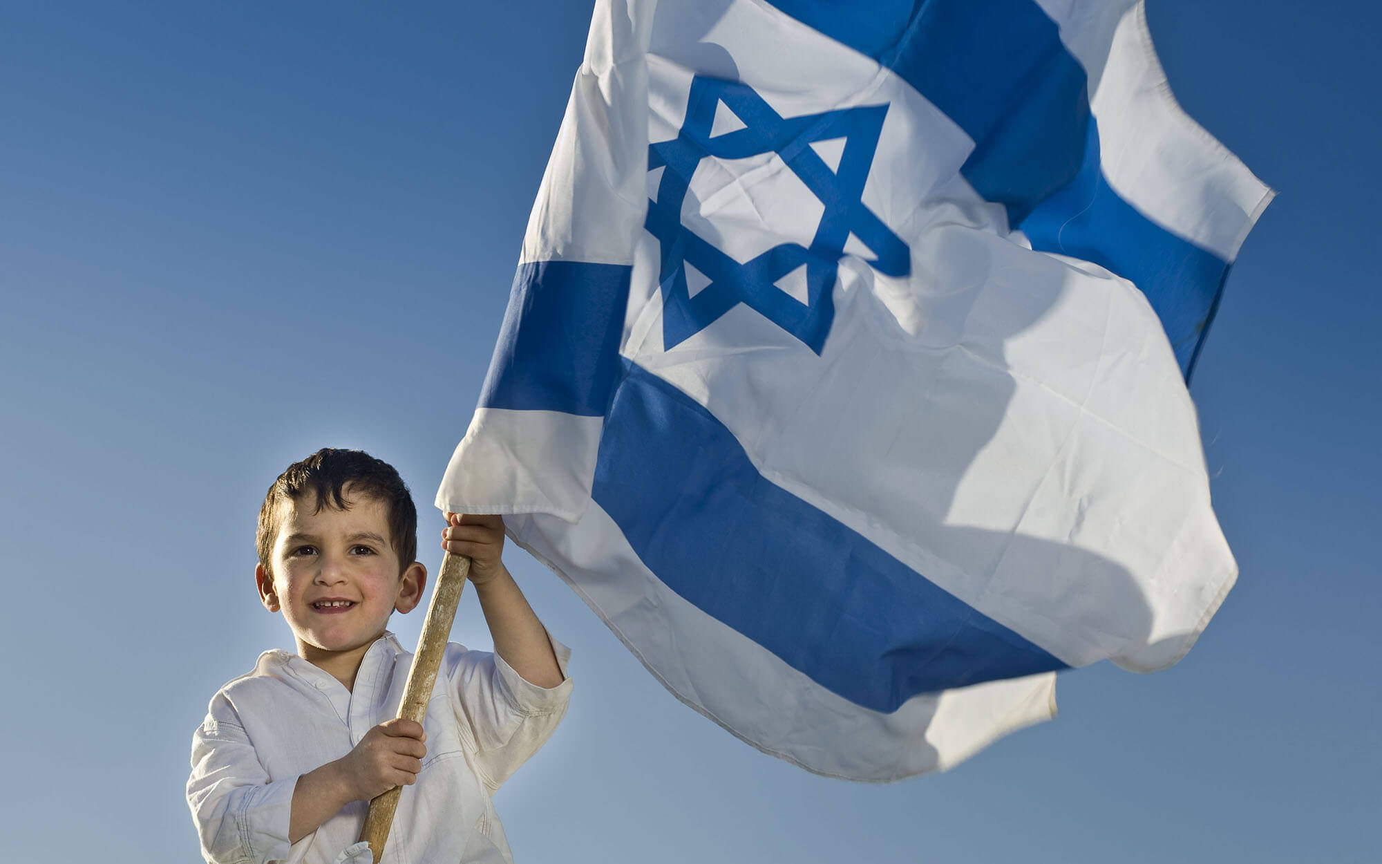 Young boy holding a large flag of Israel
