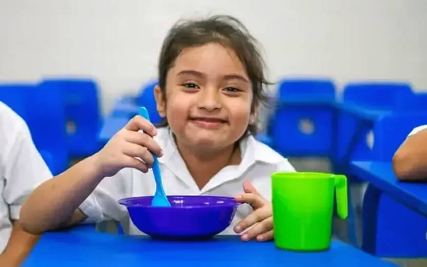 young child enjoying a meal served in a blue bowl